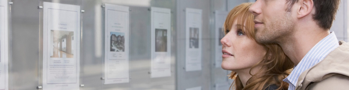 Side view of a young couple looking at window display at real estate office
